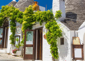 Beautiful town of Alberobello with trulli houses among green plants and flowers in the Apulia region of southern Italy.