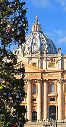 St. Peter’s Basilica dome with decorated Christmas tree foreground.