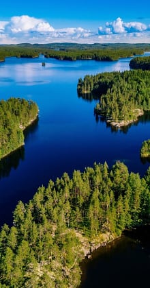 Forest-covered islands scattered across deep blue lake under cloudy sky.