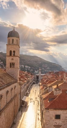 Sunlight streams over historic old town with stone bell towers.