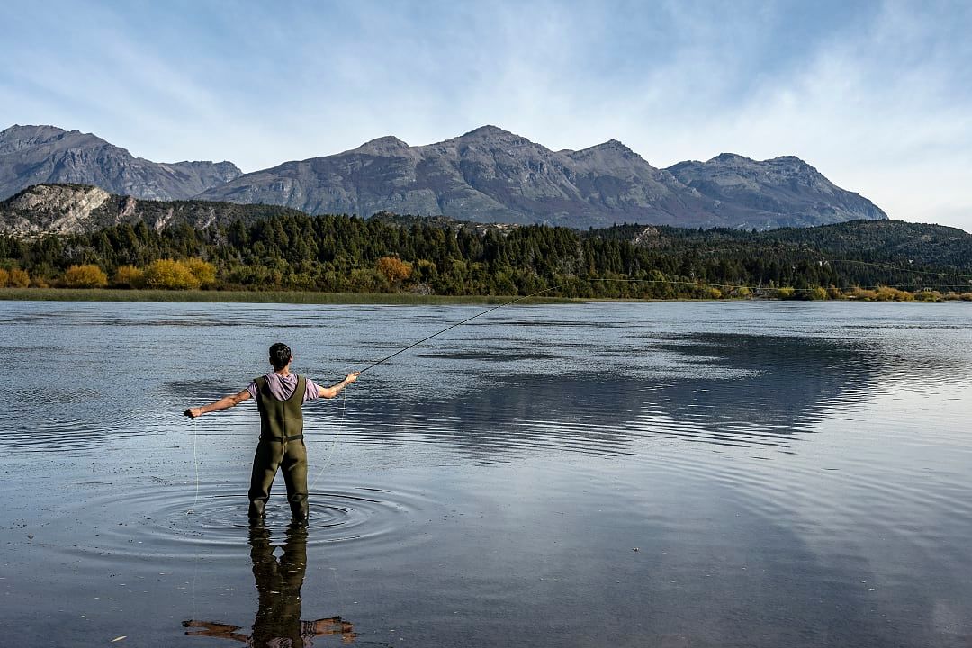 A fisherman casts his line in Patagonia’s calm, reflective waters.