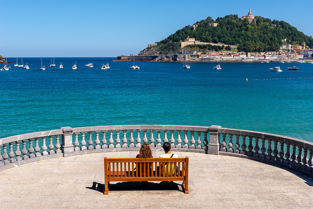 Couple sitting on a bench at the La Concha Promenade in San Sebastian, Spain