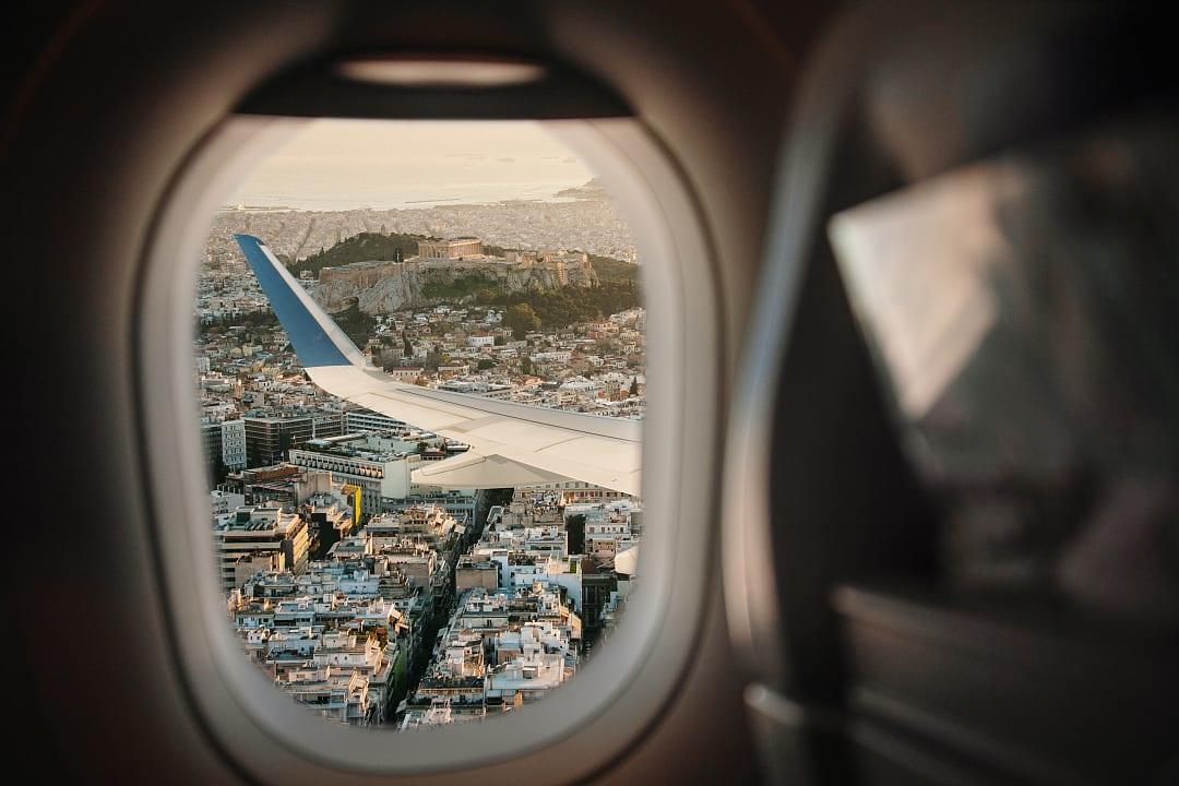 View through an airplane window of a city and coastline.