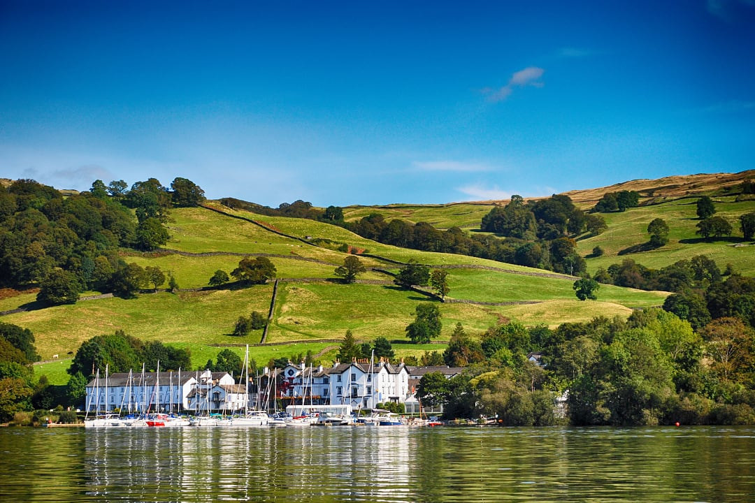 Sailboats moored at Bowness-on-Windermere Town with green rolling hills in the background