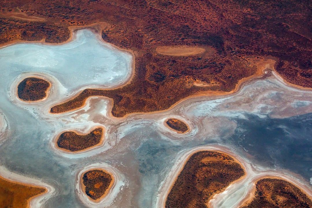 High-altitude aerial view of crystalline salt lakes and ochre-colored desert patterns in Queensland, Australia.
