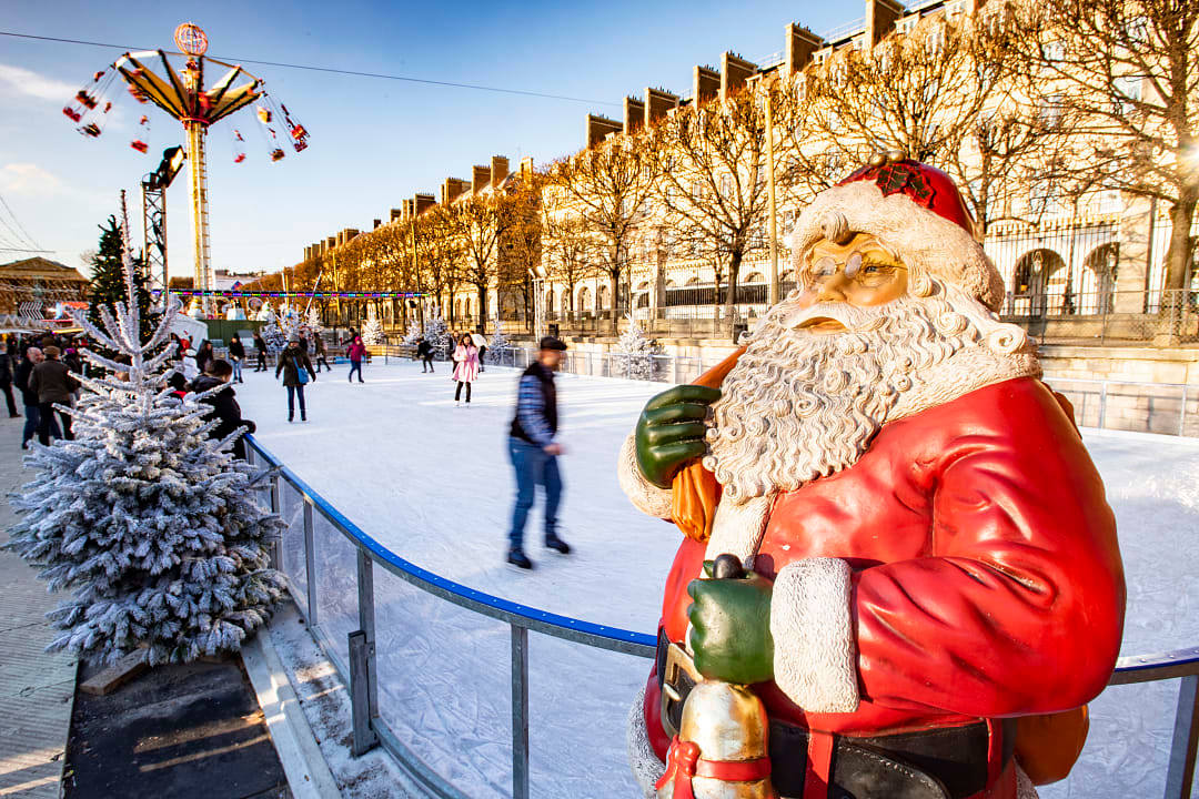 Statue of Santa Claus with people ice skating in the background at the Tuileries Christmas Market in Paris, France
