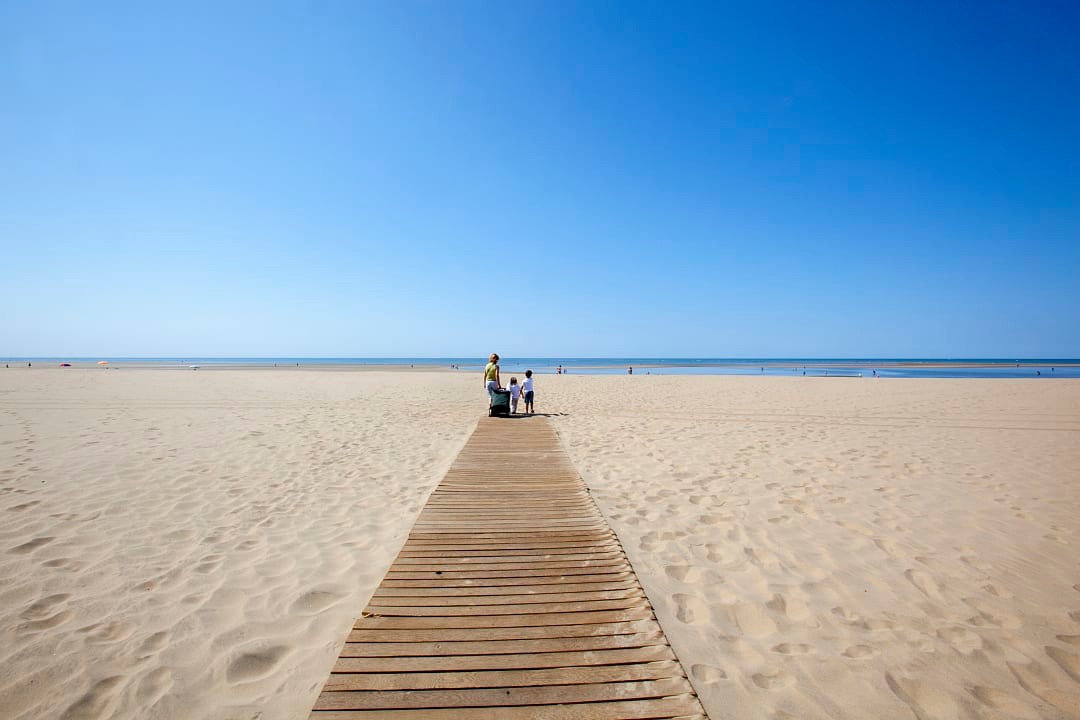 Family a the end of a walkway on the beach in Isla Canela, Spain