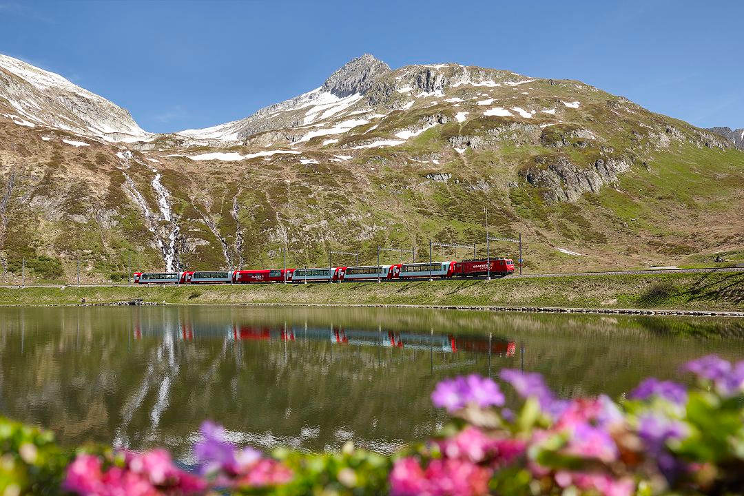 Glacier Express crossing Oberalp Lake with alpine peaks in the Swiss Alps