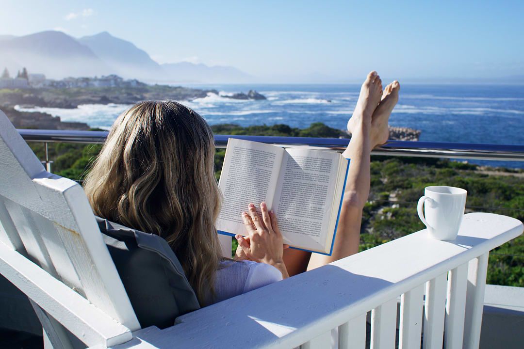 Woman relaxing and reading a book from a resort at Hermanus Beach, South Africa