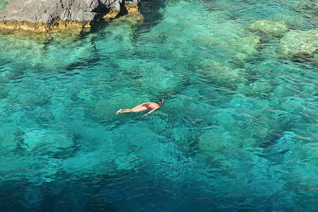 Young woman snorkeling in the turquoise waters at Plakaki Cape, Zakynthos island, Greece