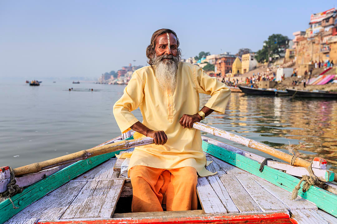 Senior sadhu sitting in wooden boat on the Ganga river