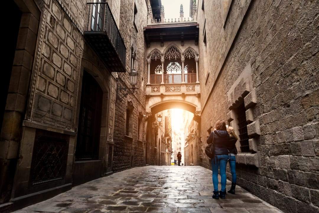 Two women dressed in winter jackets photographing the gothic architecture in Barcelona, Spain