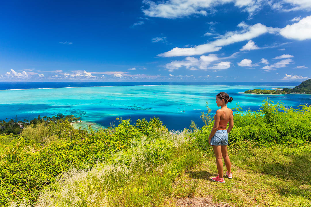 A woman admiring the blue waters from a viewpoint in Bora Bora.
