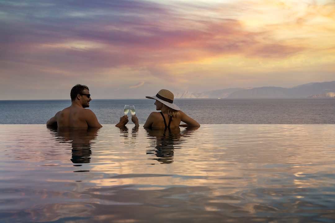 Couple enjoying a sunset from a pool in Greece.