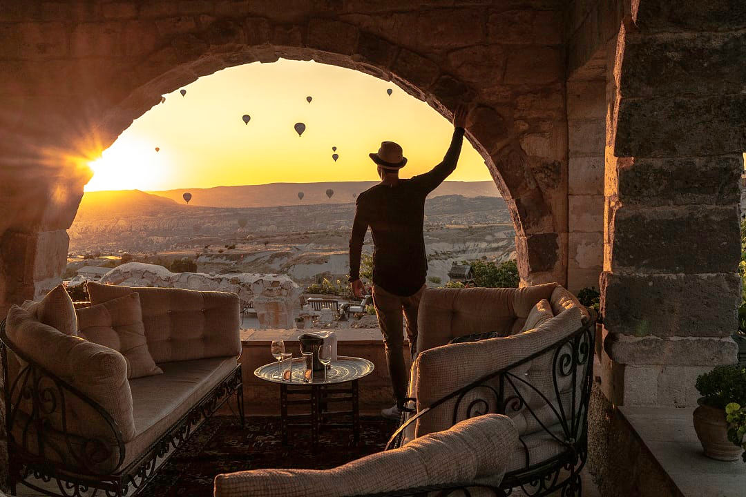 A traveler admires Cappadocia’s sunrise with floating hot air balloons.