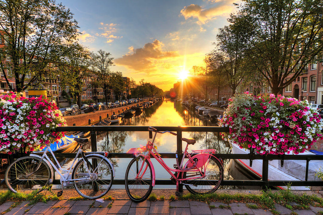 Bikes parked on a canal bridge during sunrise in Amsterdam, the Netherlands
