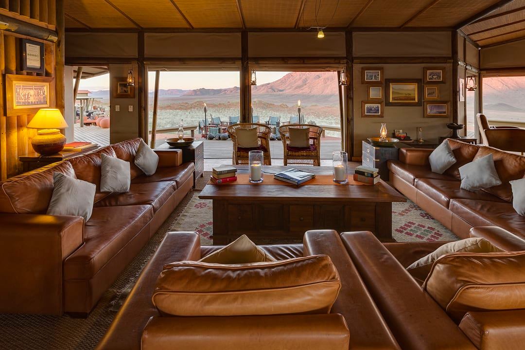 Scenic view of luxury lodge in Namibia's NamibRand Nature Reserve, surrounded by vast desert landscape and rolling sand dunes.