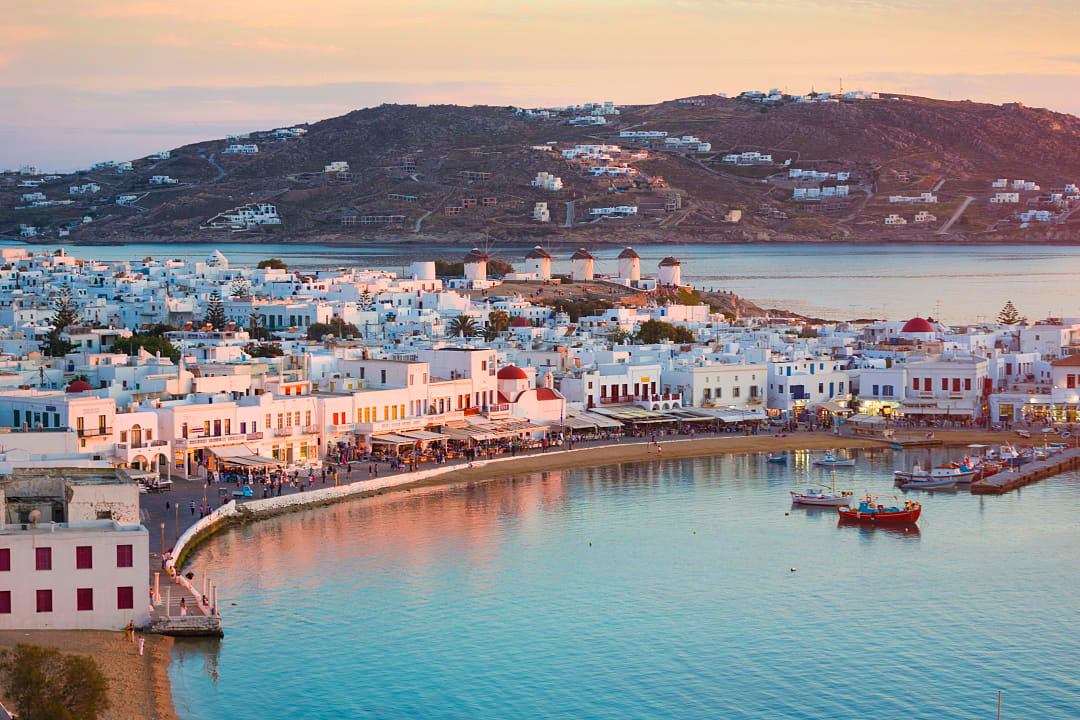 Colorful waterfront and windmills at sunset in Mykonos, Greece.