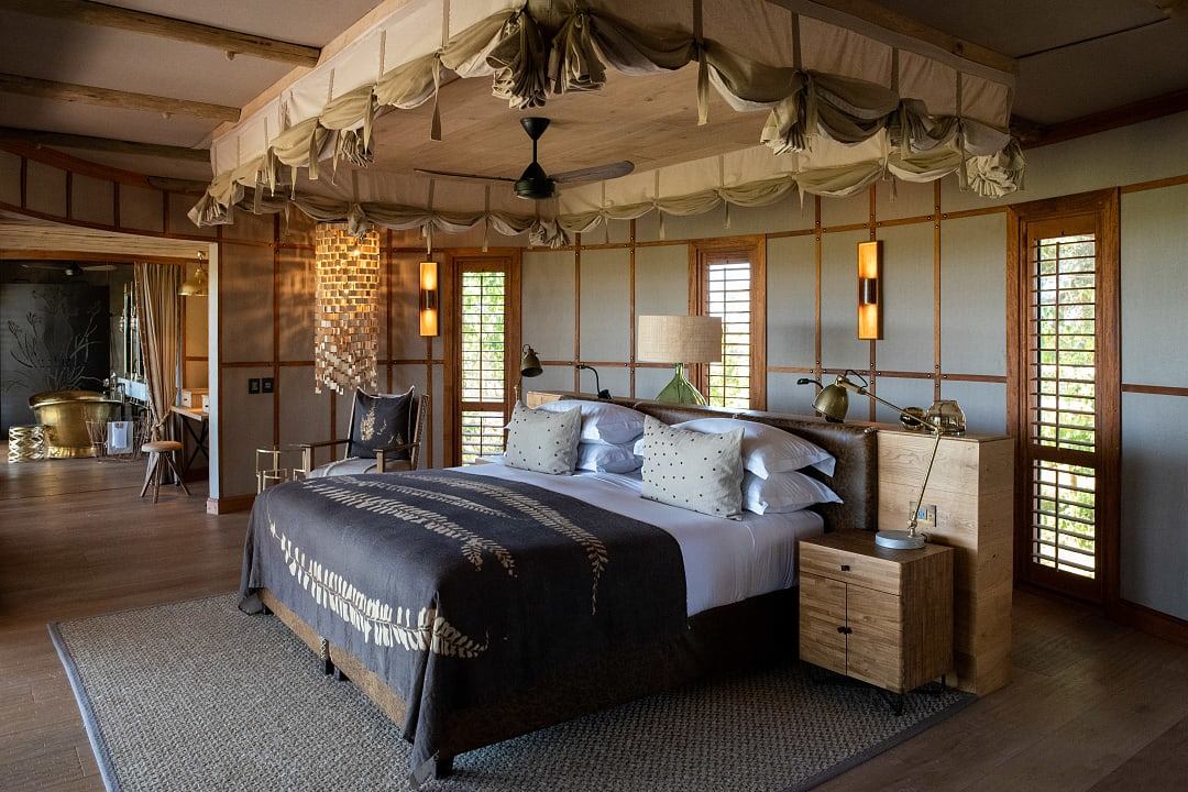Luxury safari lodge suite with canopy bed and elegant natural décor.