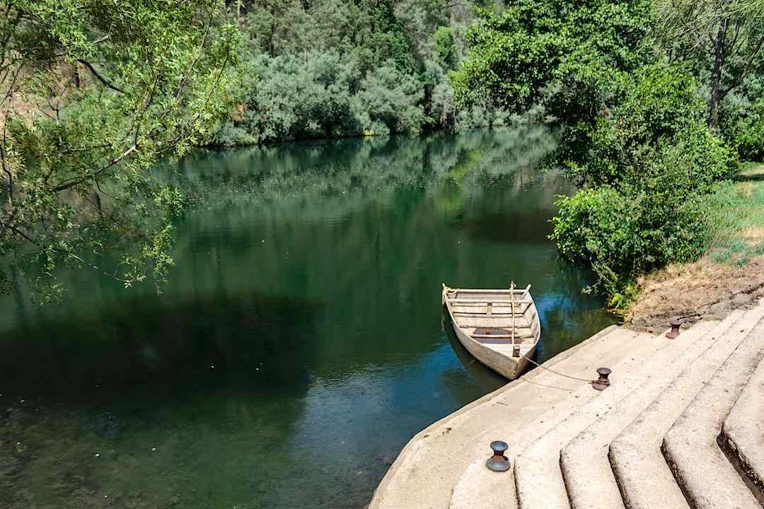 Wooden boat moored on a peaceful, forest-lined river in central Portugal