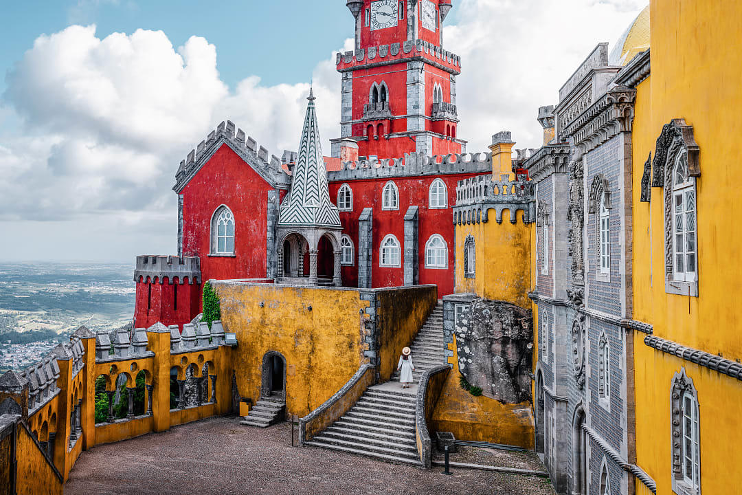 Woman standing on the stairs at the colorful Pena Palace in Sintra, Portugal