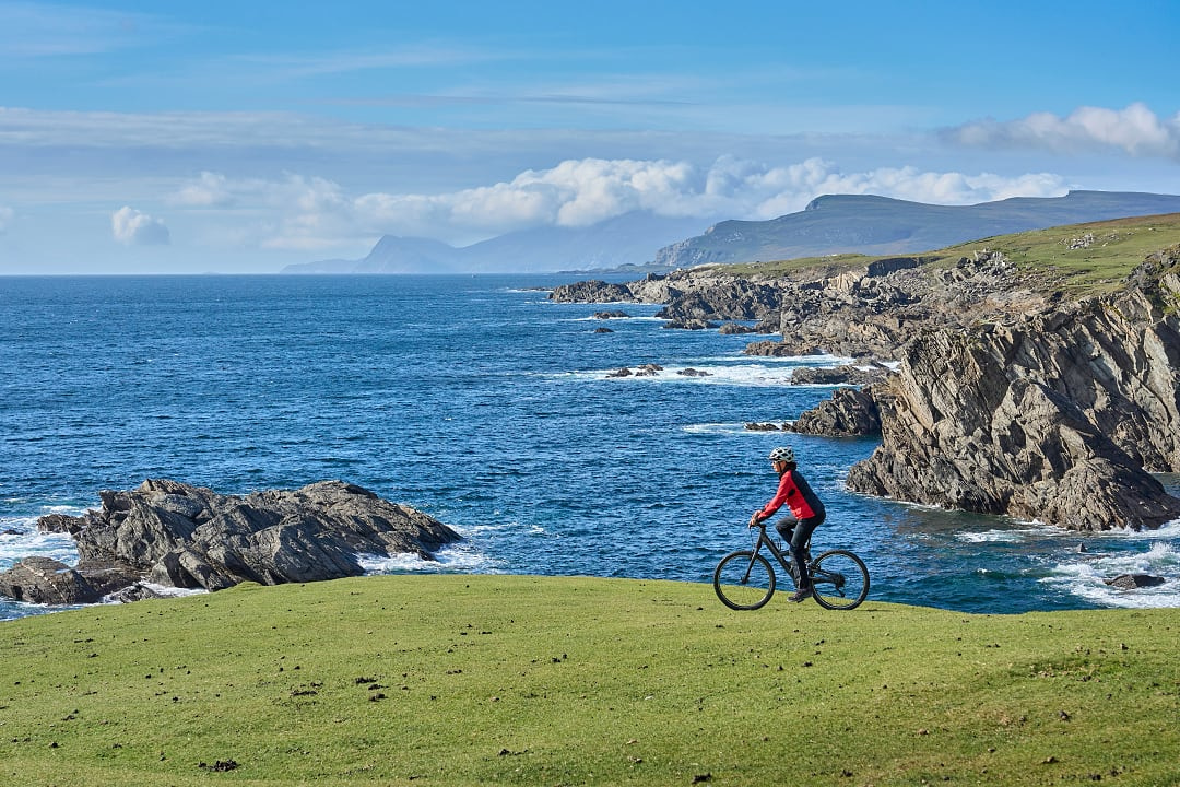Senior woman cycling the cliffs of Achill island on the Wild Atlantic Way in Ireleand