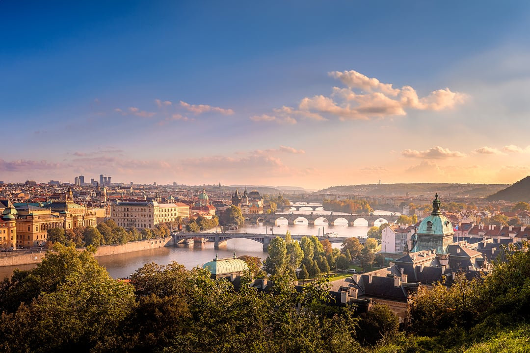 Scenic view of Prague at sunset with iconic bridges, the Vltava River, and historic architecture