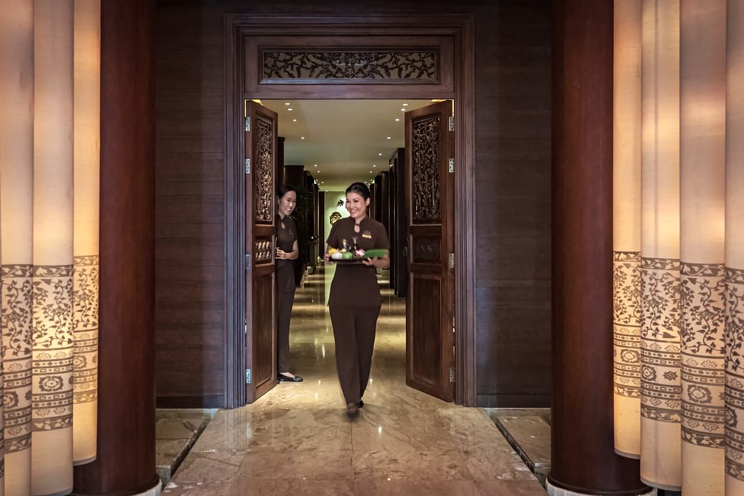Spa attendant welcoming guests at The Peninsula Hotel spa in Bangkok, Thailand