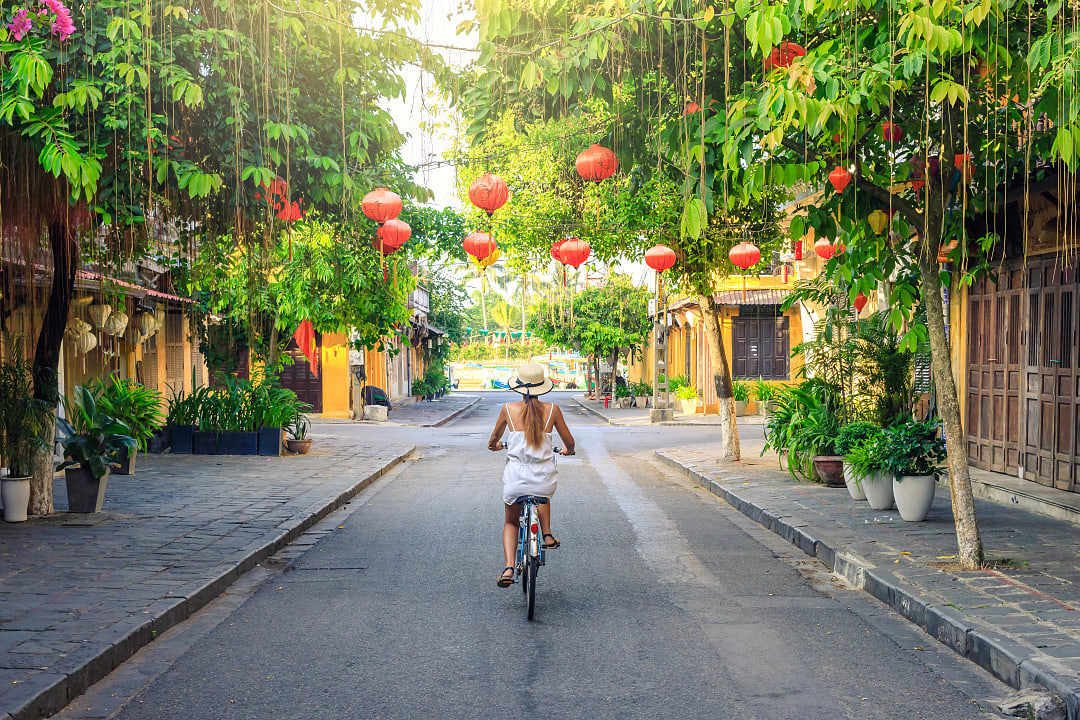 Cyclist riding through lantern-lined street in Hoi An Ancient Town, Vietnam