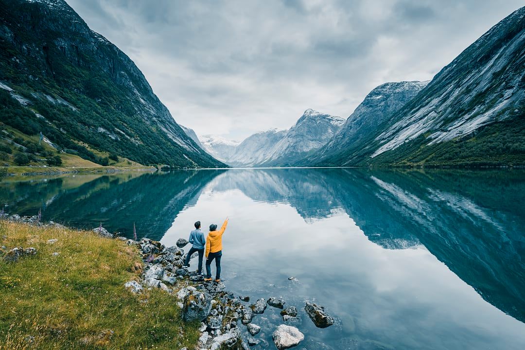 Two people standing by the still waters of the fjords in Norway.