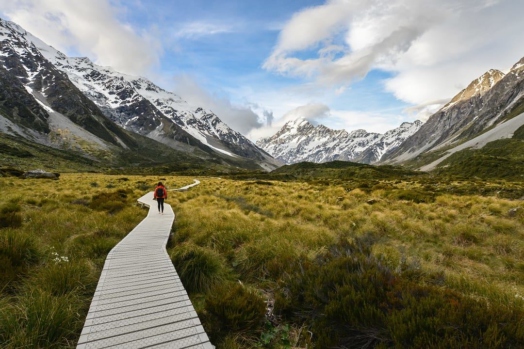 Wooden boardwalk leading toward snow-capped peaks in Aoraki Mount Cook National Park.