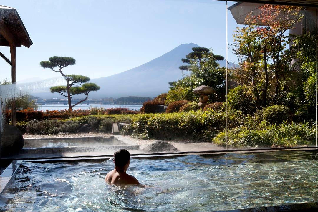 Man at an onsen relaxing and enjoying the view of mt fuji at Lake Kawaguchi, Japan