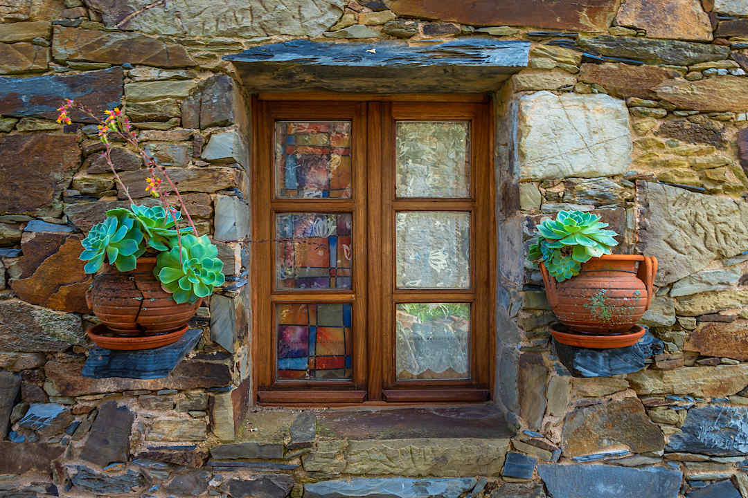 Wooden window and potted succulents on a traditional schist house in Portugal