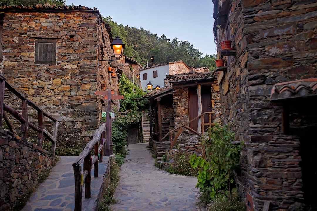 Lantern-lit lane between traditional stone houses in a Portuguese schist village