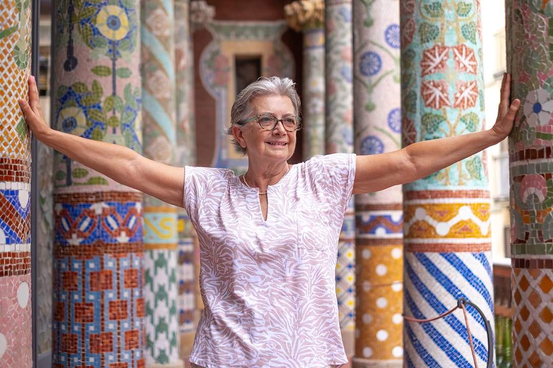Senior woman leaning on the colorful mosaic columns at Palace of Catalan Music in Barcelona, Spain