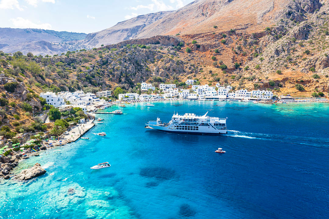 White ferry boat approaching a coastal village with turquoise water.