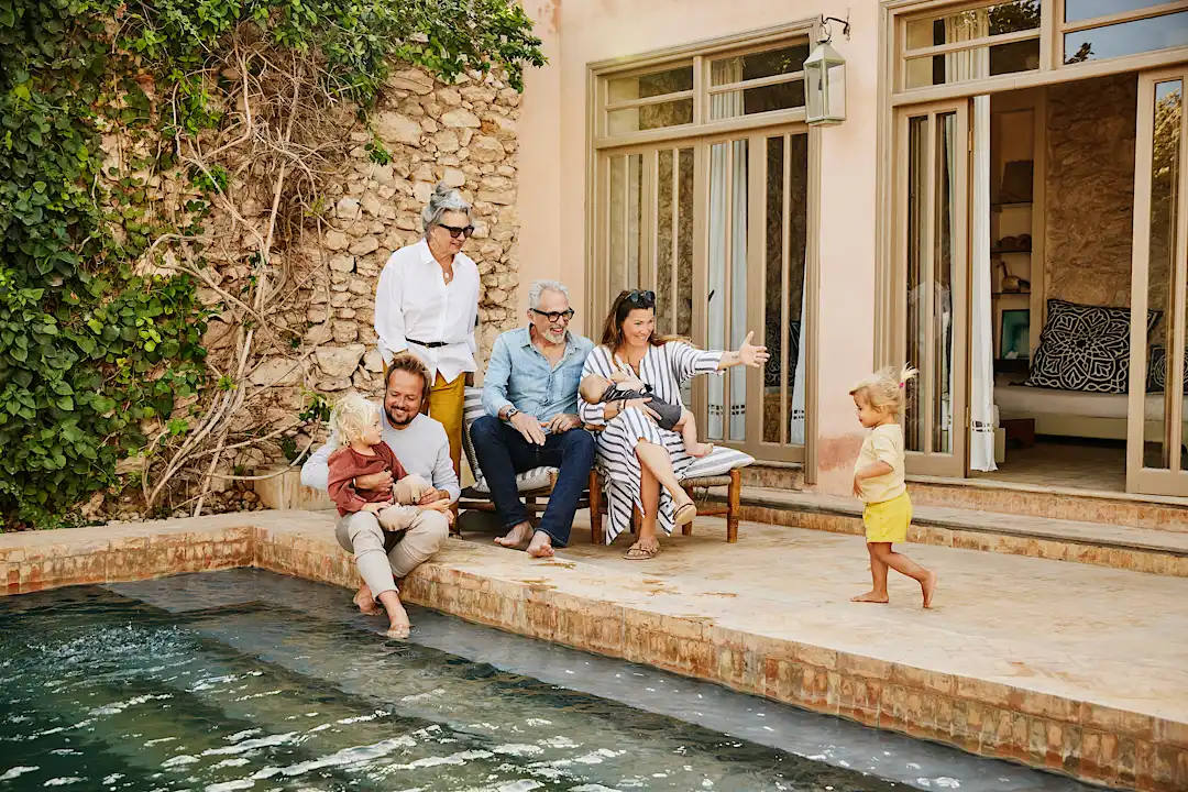Multi-generational family gathers in communal villa space with private corners