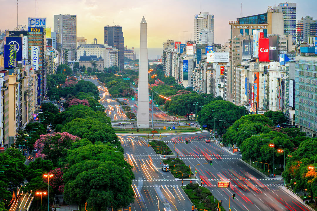 View of the iconic Obelisk of Buenos Aires, surrounded by bustling traffic on Avenida 9 de Julio, Argentina.