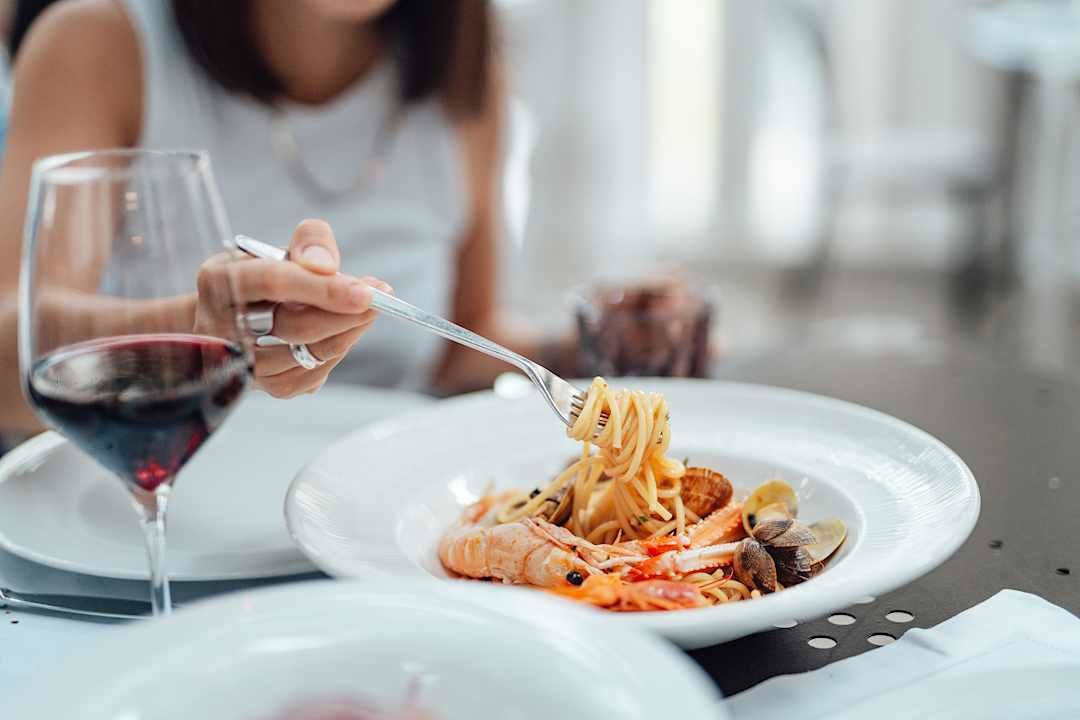 Woman enjoying a seafood pasta in Italy.