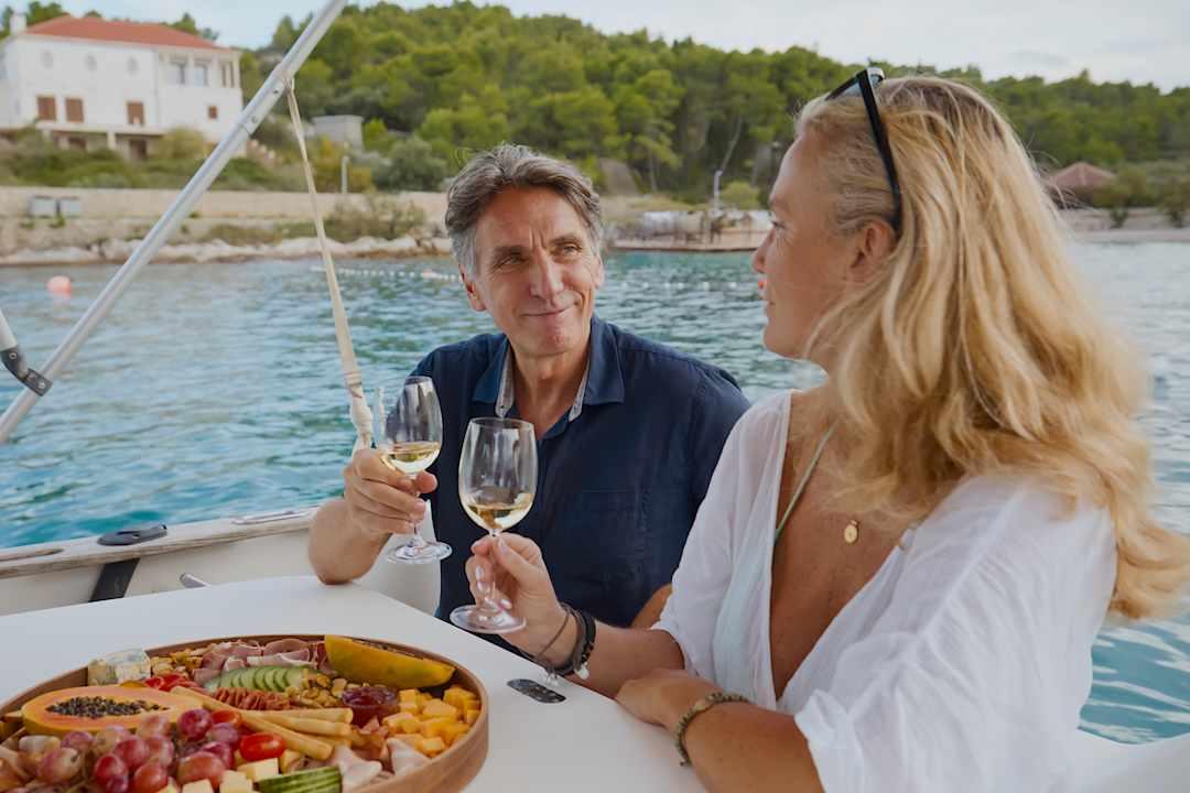 Couple enjoying food and wine on a yacht in the Dalmatian Coast, Croatia. 