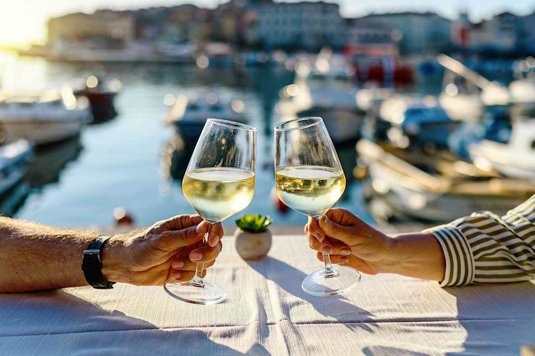 Couple toasting with white wine at a waterfront restaurant in coastal Croatia