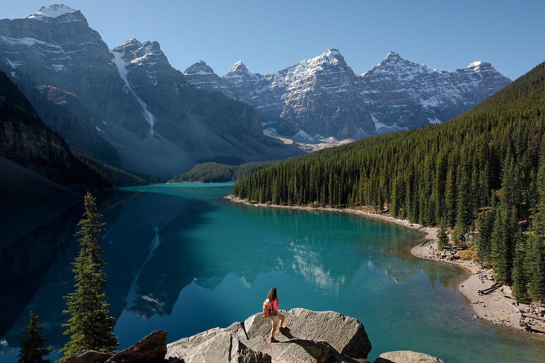 A traveler admires Moraine Lake’s turquoise waters and towering mountains.