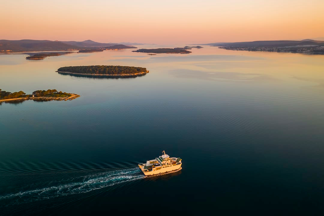 A ferry glides through Dalmatia’s calm waters, surrounded by stunning islands. 