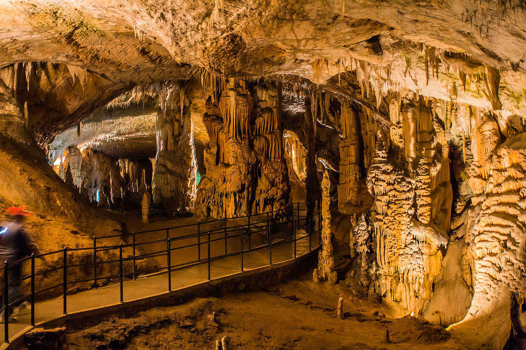 Illuminated underground limestone cave formations with walkway