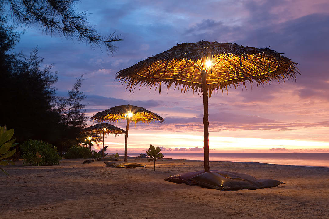 The sun sets over the beach of a lavish seaside resort.