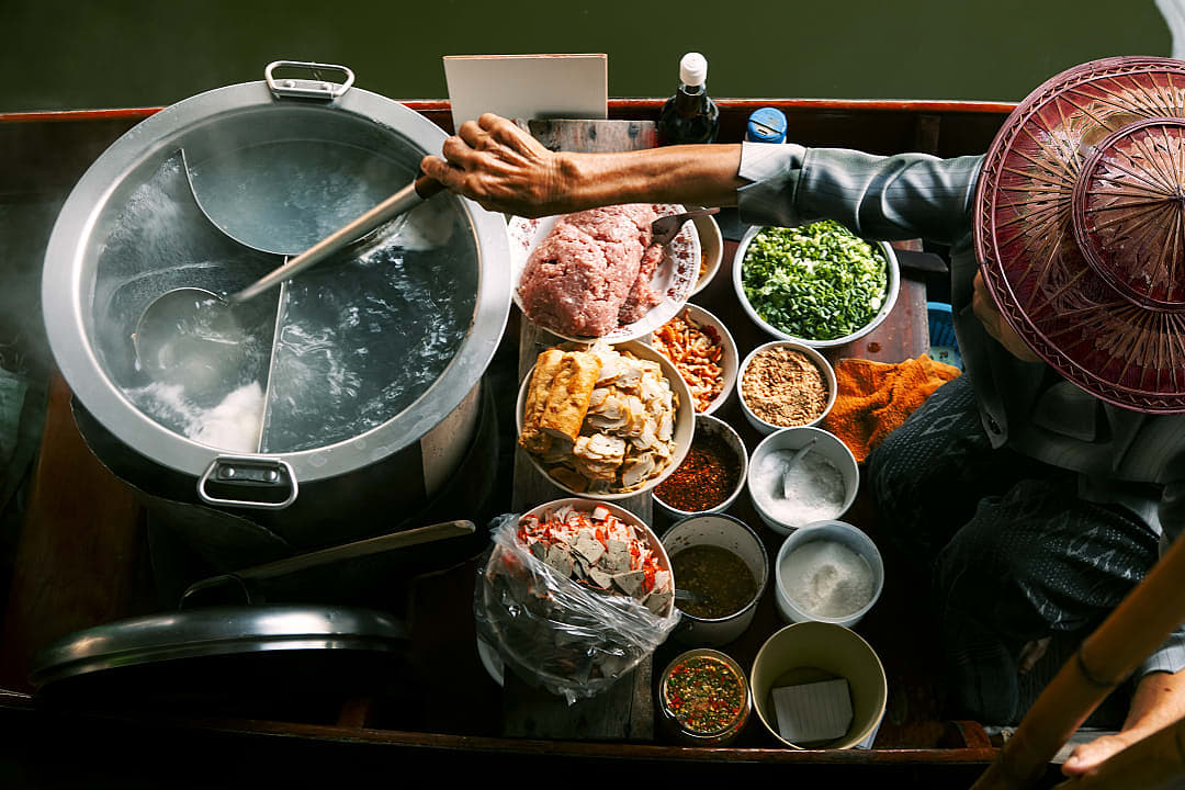 Woman preparing noodles on boat in floating market, Bangkok, Thailand