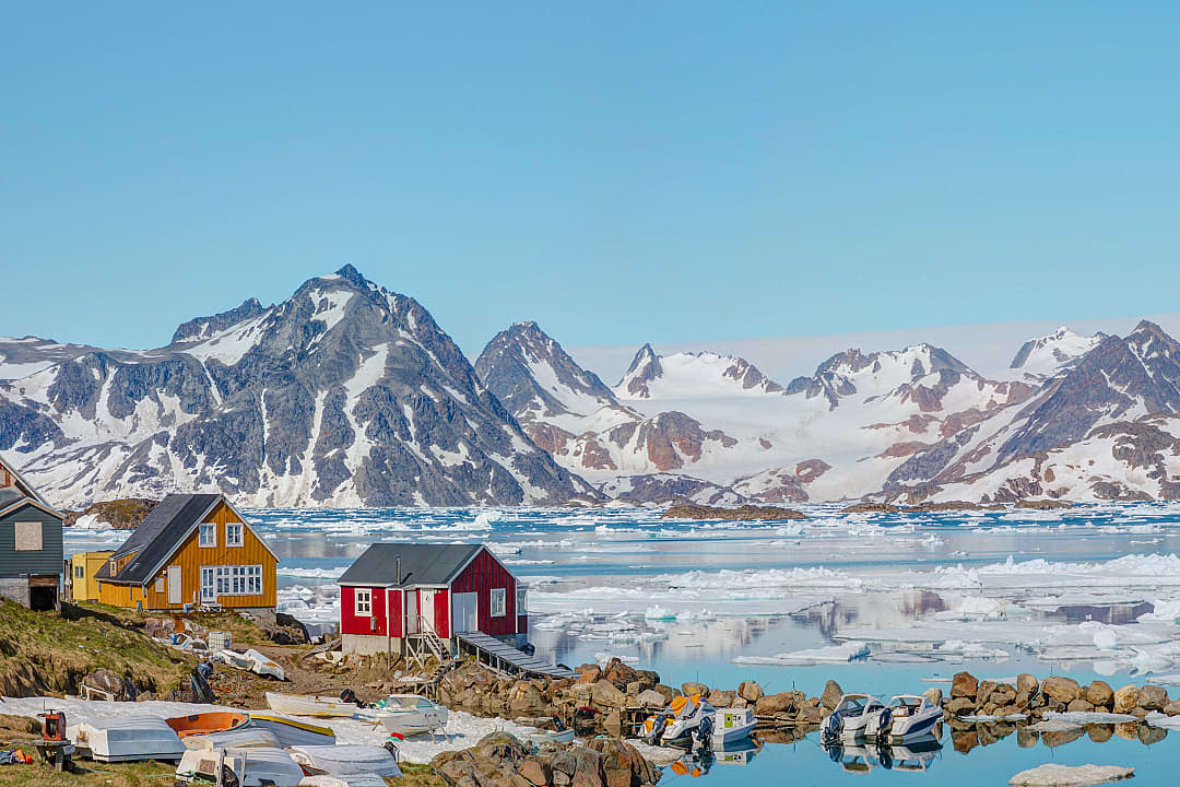 Colorful coastal houses in Iceland, framed by snow-capped mountains.