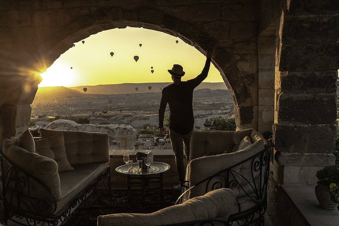 A traveler admires Cappadocia’s sunrise with floating hot air balloons.