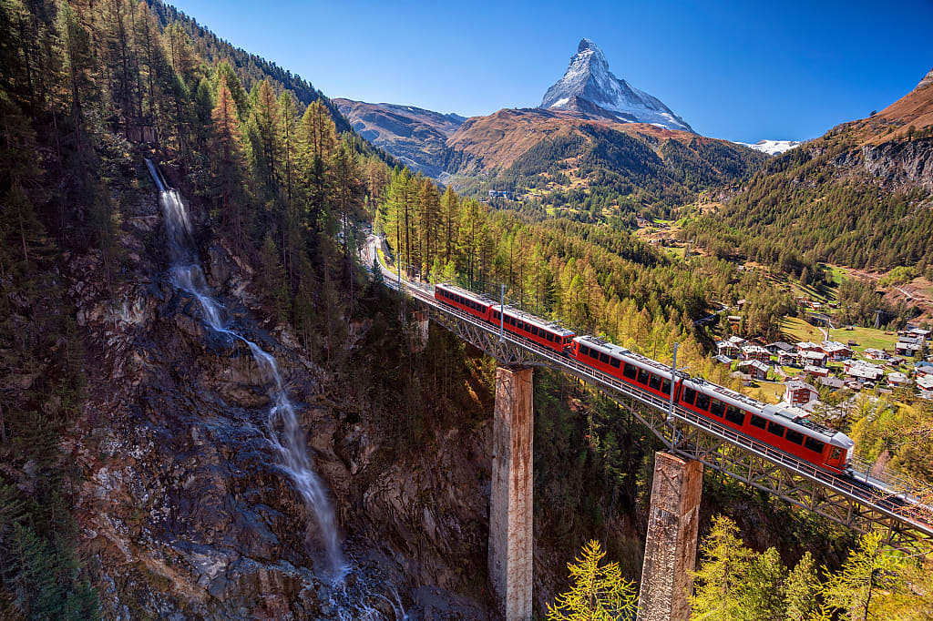 Gornergrad tourist train passing waterfall and matterhorn in Switzerland