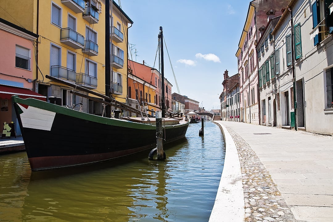 Colorful canal-side buildings and boat in Comacchio, a charming town in northern Italy